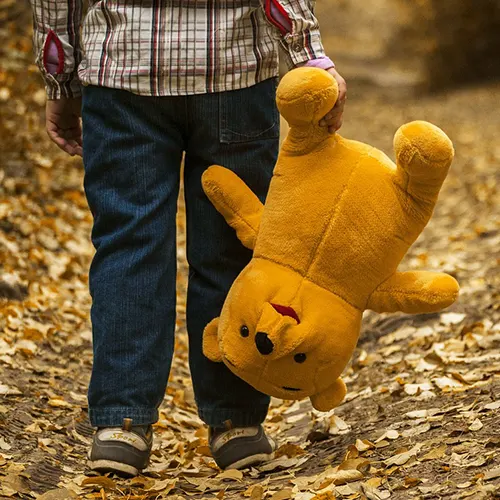 Underkroppen til et barn som holder en bamse i hånda